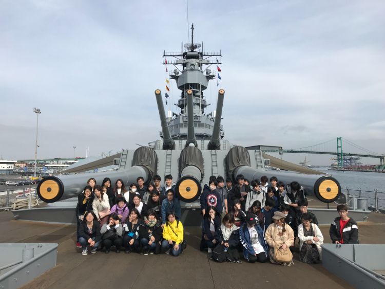 戦艦の前で記念撮影する学生たち