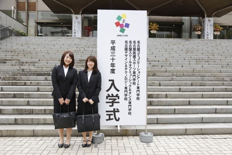 入学式の看板の前で記念撮影する学生