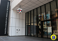左側に、青色の建物に「NCA」の文字が入った建物が、名古屋デザイン＆テクノロジー専門学校です。
